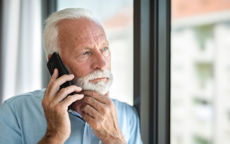 serious older man talking on phone