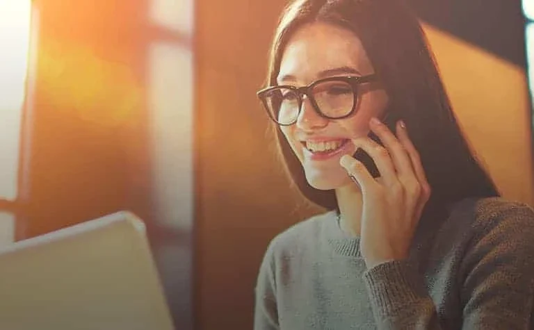 smiling woman talking on phone orange background
