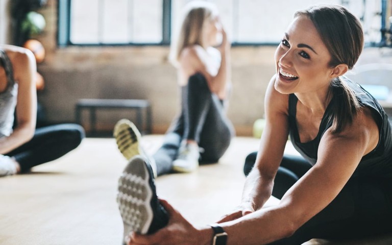 smiling woman stretching in gym