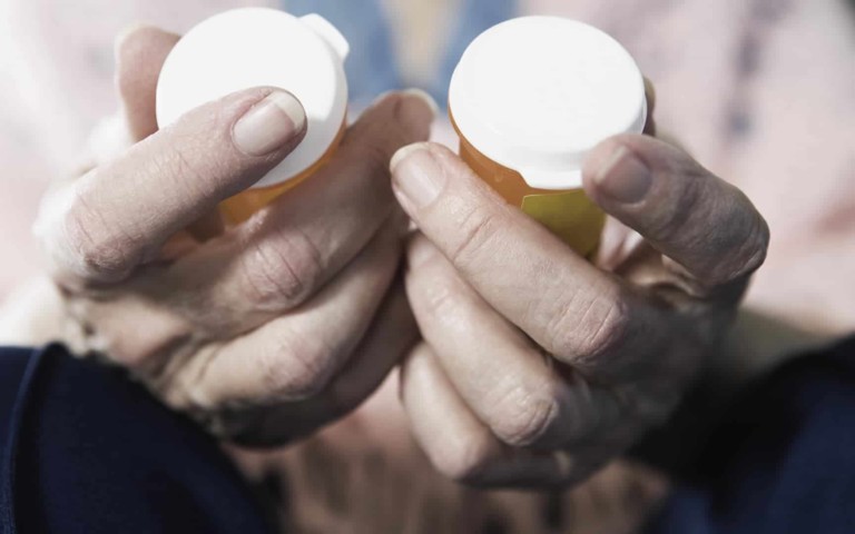 old hands holding prescription bottles