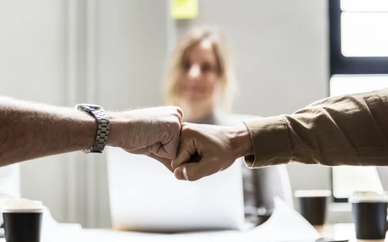 men fistbumping in front of woman at conference table