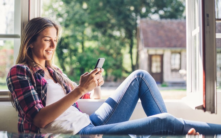 smiling woman leaning back holding phone
