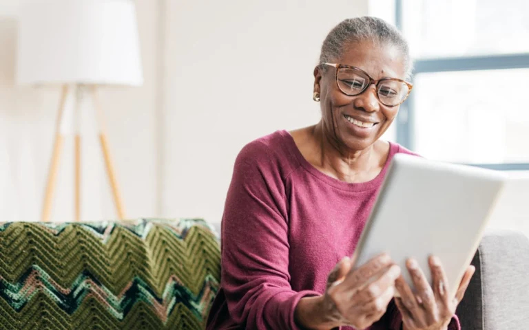 smiling older woman on couch holding tablet