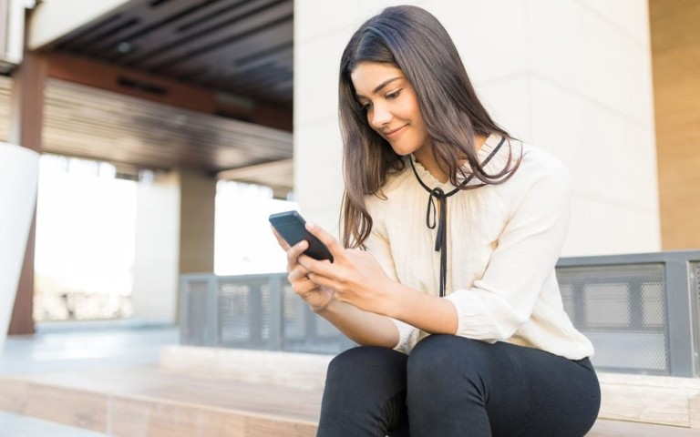 woman sitting on stairs looking at phone