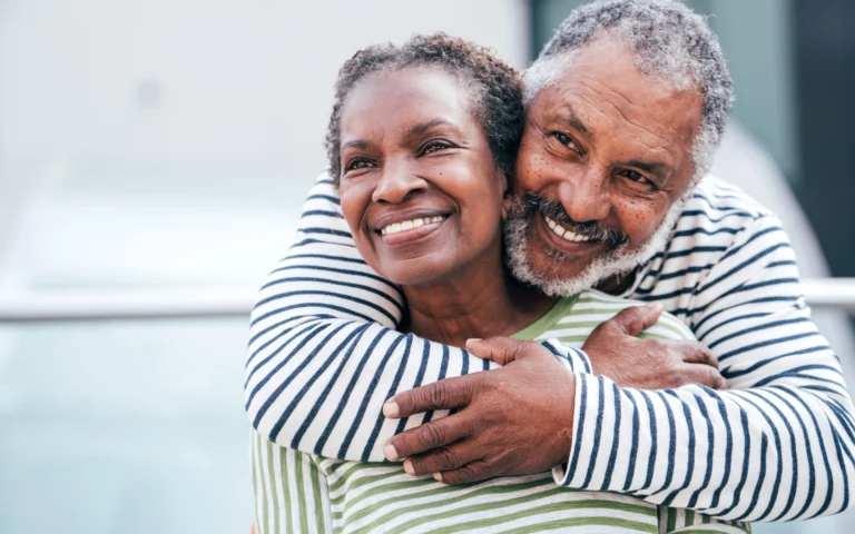 older smiling black couple hugging