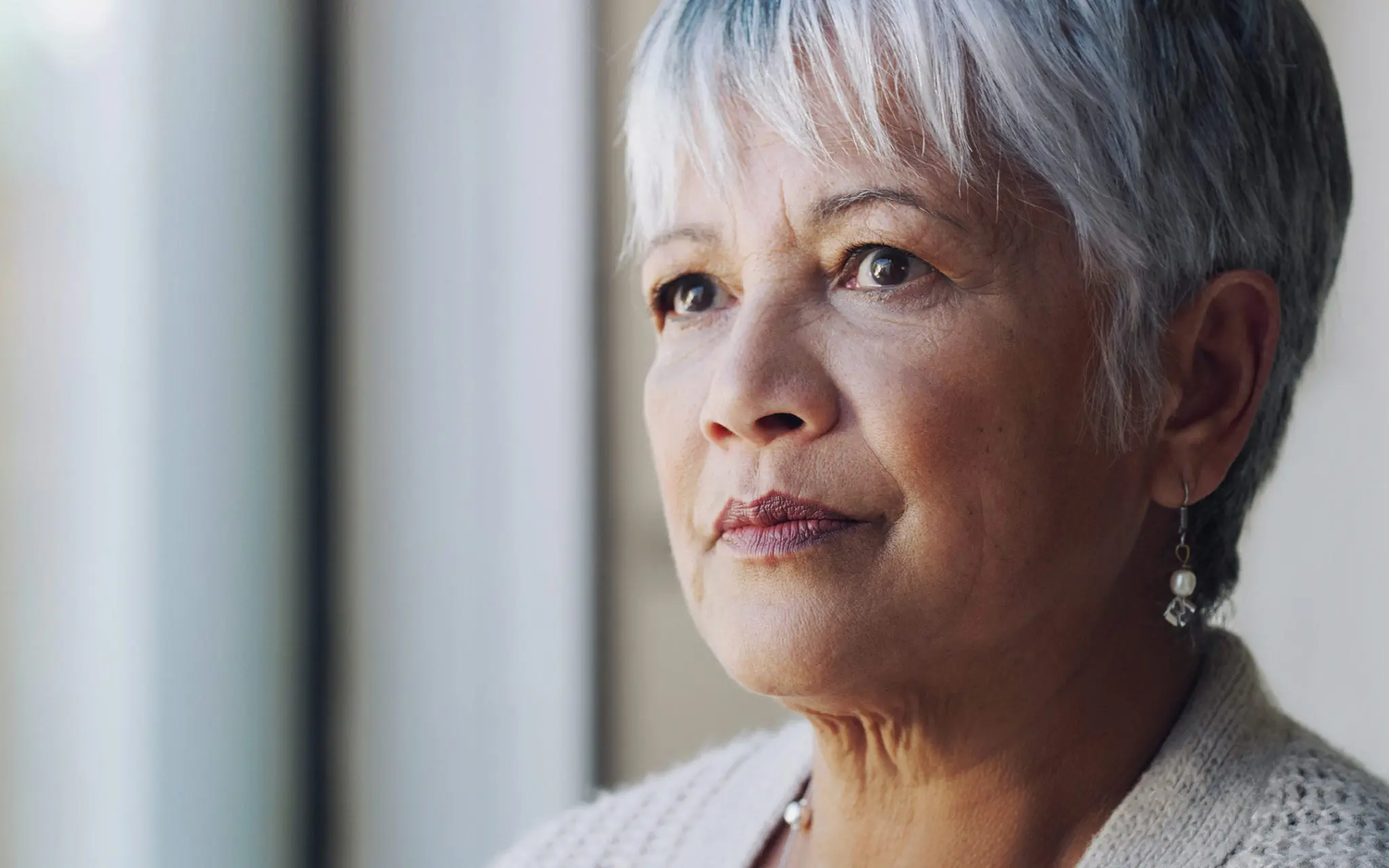 Thoughtful older woman looking out window