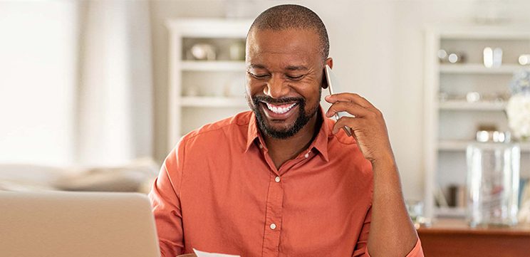 smiling man using mobile phone and reading a note