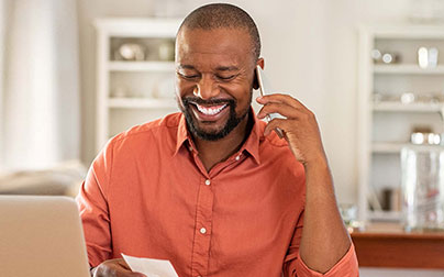 smiling man using mobile phone and reading a note