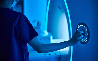 Radiology technician operating MRI scanner controls at a hospital imaging center