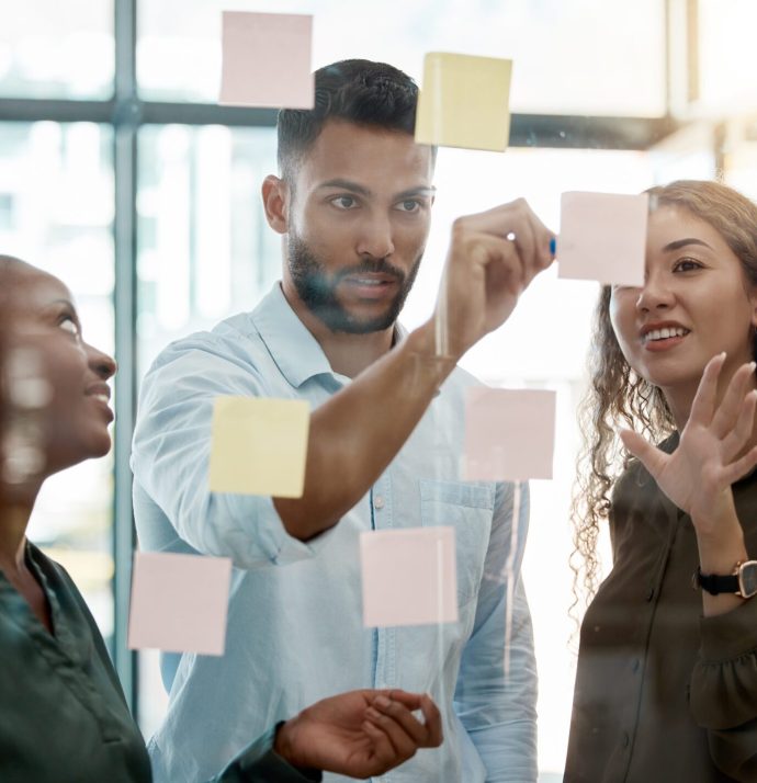 Team strategy meeting on research, post it on glass wall and group work planning together. Business people brainstorming analytics vision think tank ideas, collaboration thinking and sticky notes